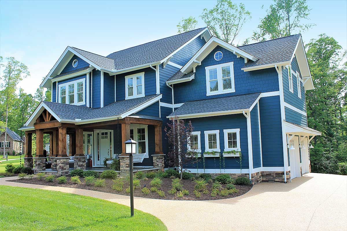 House plan exterior: Two-story, blue siding, prominent wood-columned front porch with stone base, multiple gables.