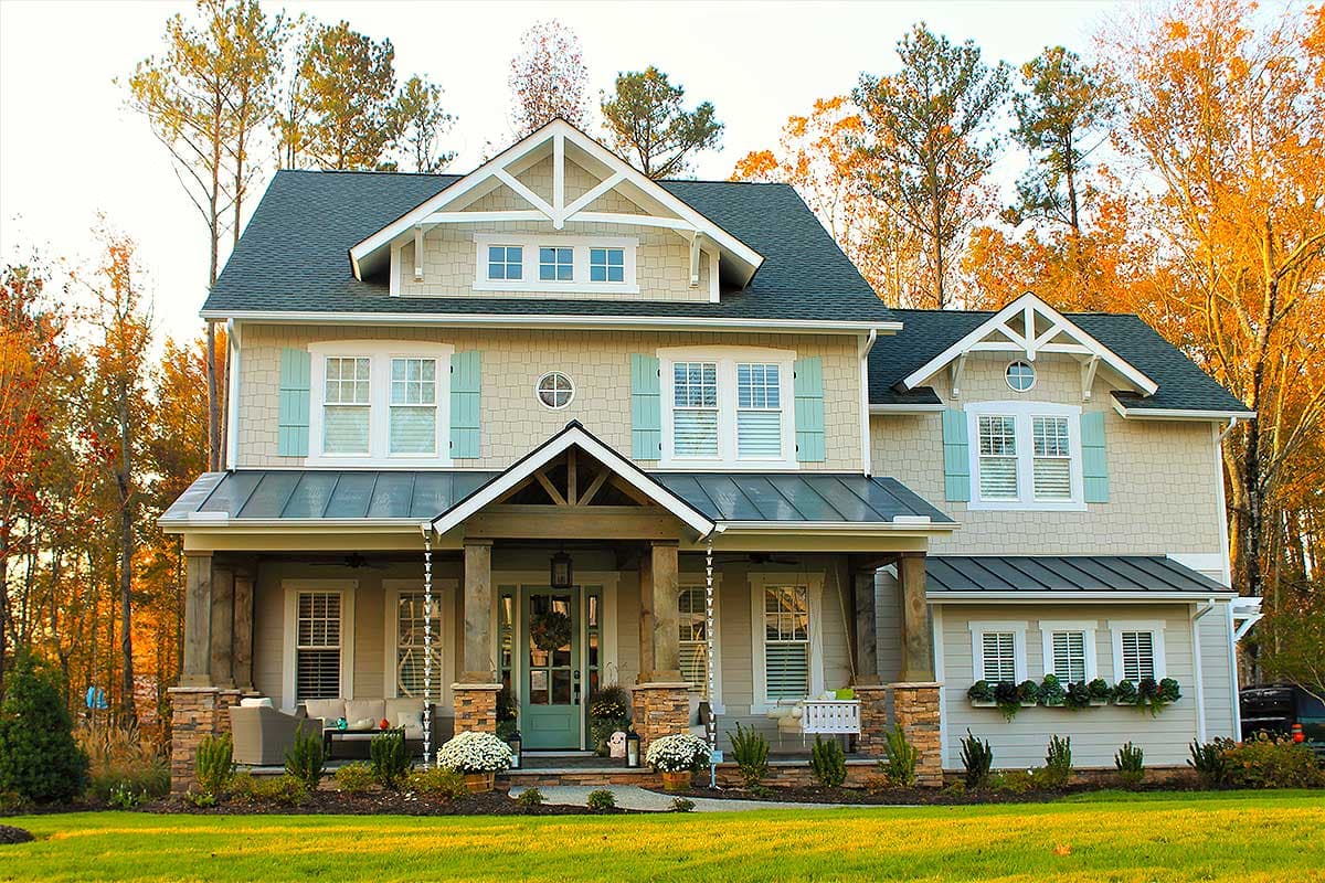 Craftsman style house plan exterior with two stories, gables, dormers, stone-clad porch columns, and a metal roof.