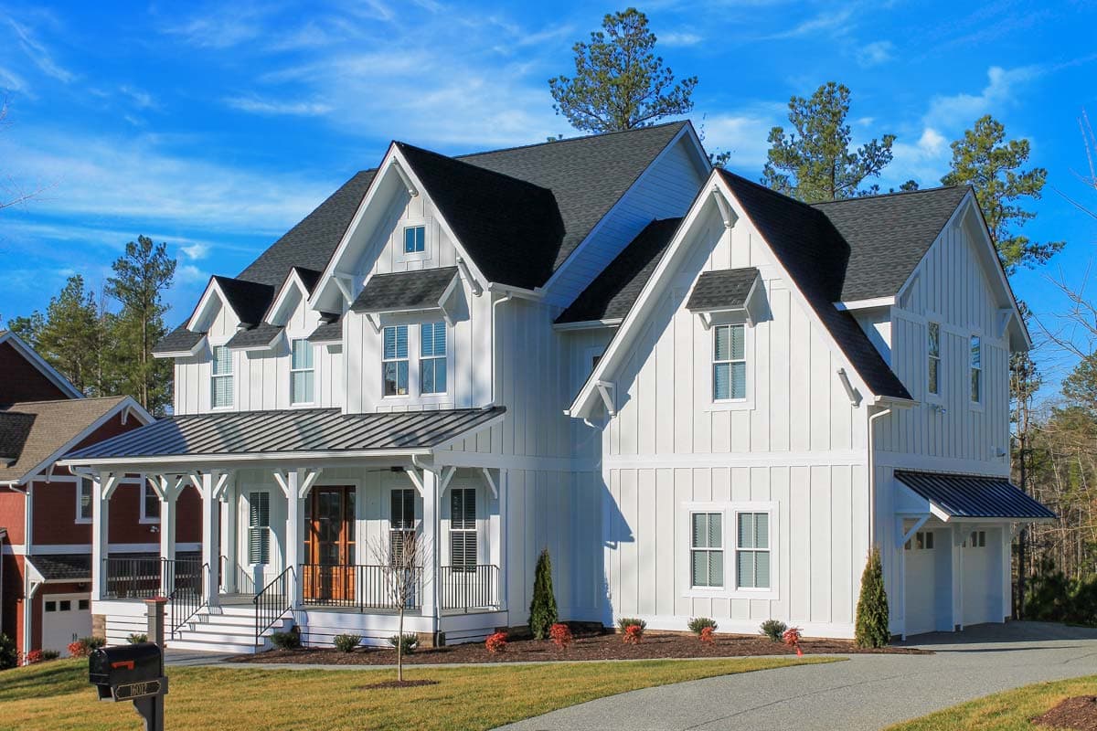 House plan exterior. Two-story Modern Farmhouse with gabled roof, dormers, and a covered porch. Attached two-car garage visible.