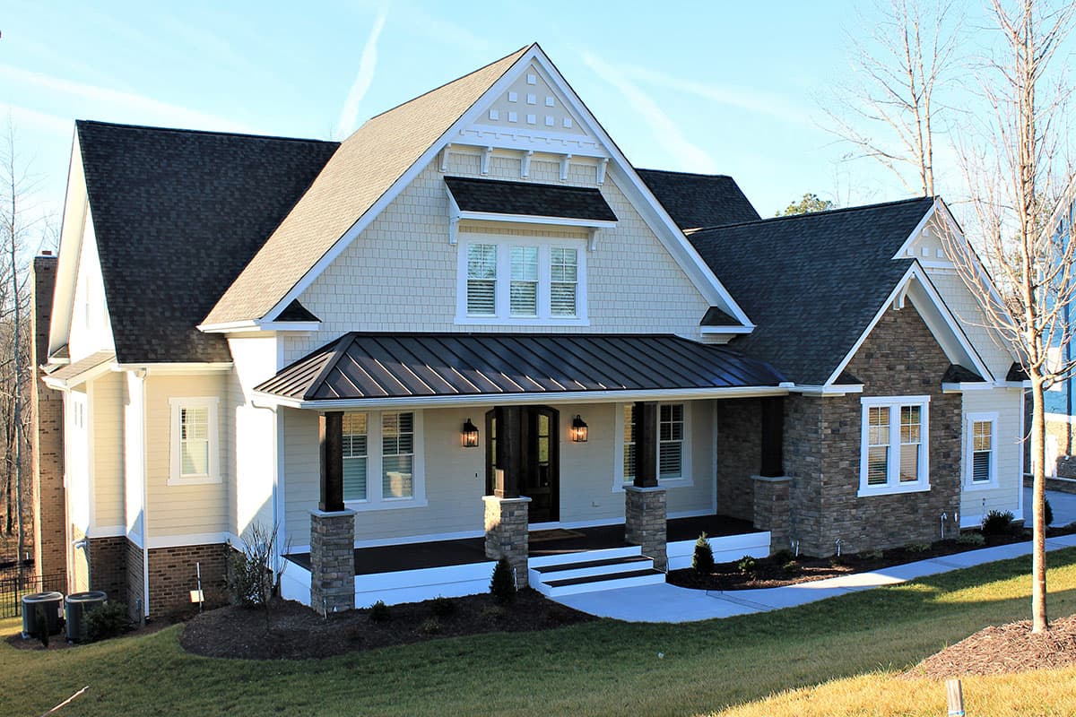 House plan exterior: Two-story Modern Farmhouse with gabled dormer, stone accents, and covered porch with dark wood posts.