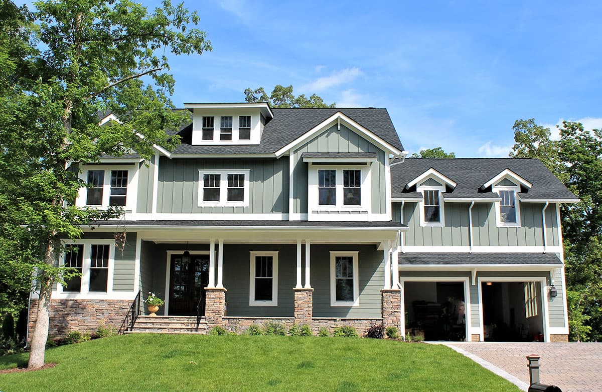 House plan exterior. Two-story Craftsman home with a front porch, gabled roof, and two dormers. Attached two-car garage is on the right.