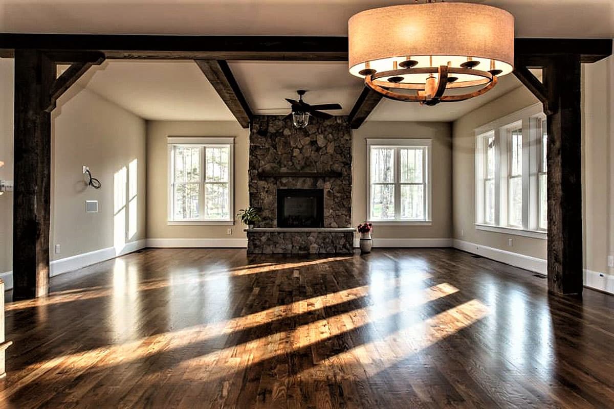 Interior view of a great room featuring a stone fireplace, exposed wood beams, and hardwood floors.