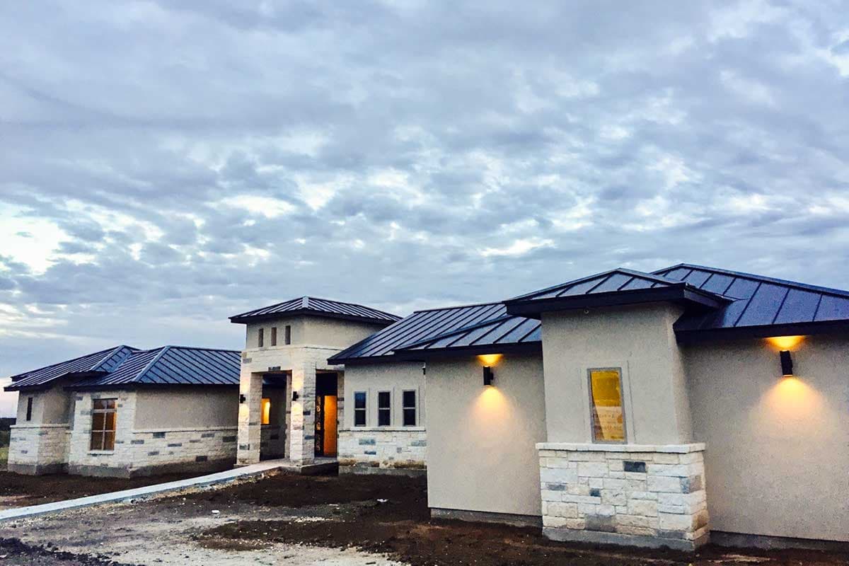 House plan exterior with a stucco and stone facade, multiple gables, and a prominent central tower.