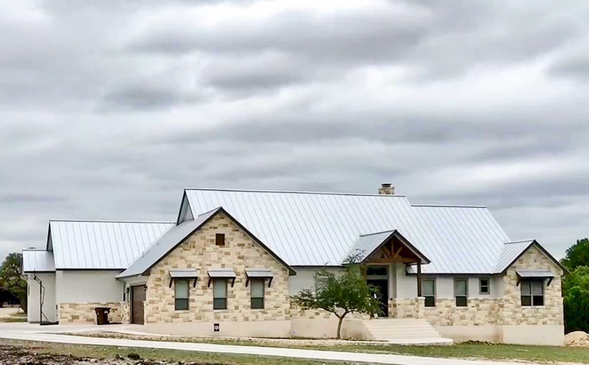 House plan exterior featuring stone accents, a metal standing seam roof, gables, and a covered entryway with exposed wood beams.