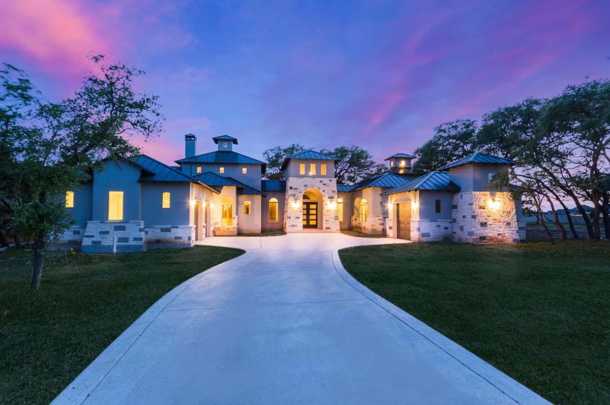 House plan exterior. Two-story Mediterranean style with metal roof. Features include turret detail, arched entry, and stone accents.