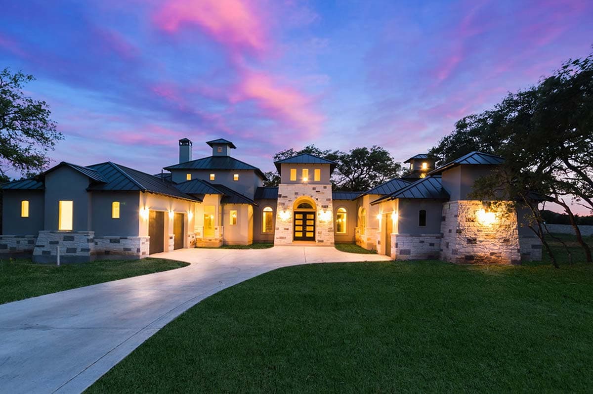 House plan exterior with multiple gables, a central tower, stone accents, and a three-car garage.