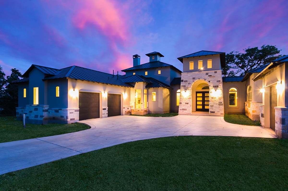 House plan exterior featuring a stone-accented facade, prominent gables, a central tower, and a three-car garage.