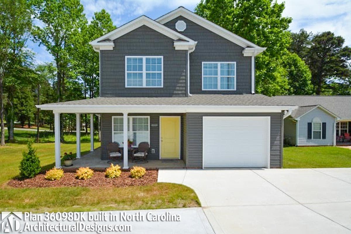 Two-story house plan exterior with gray siding, prominent front porch, white-trimmed windows, and attached garage.