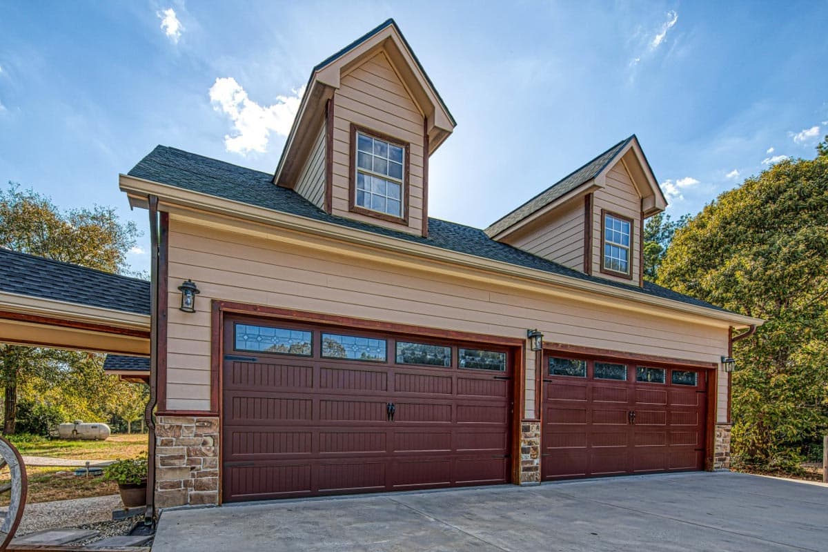 House plan exterior featuring a two-car garage with dormer windows and stone accents.