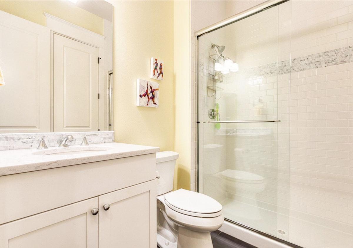 Bathroom with vanity, toilet, and glass-enclosed shower with white subway tile.