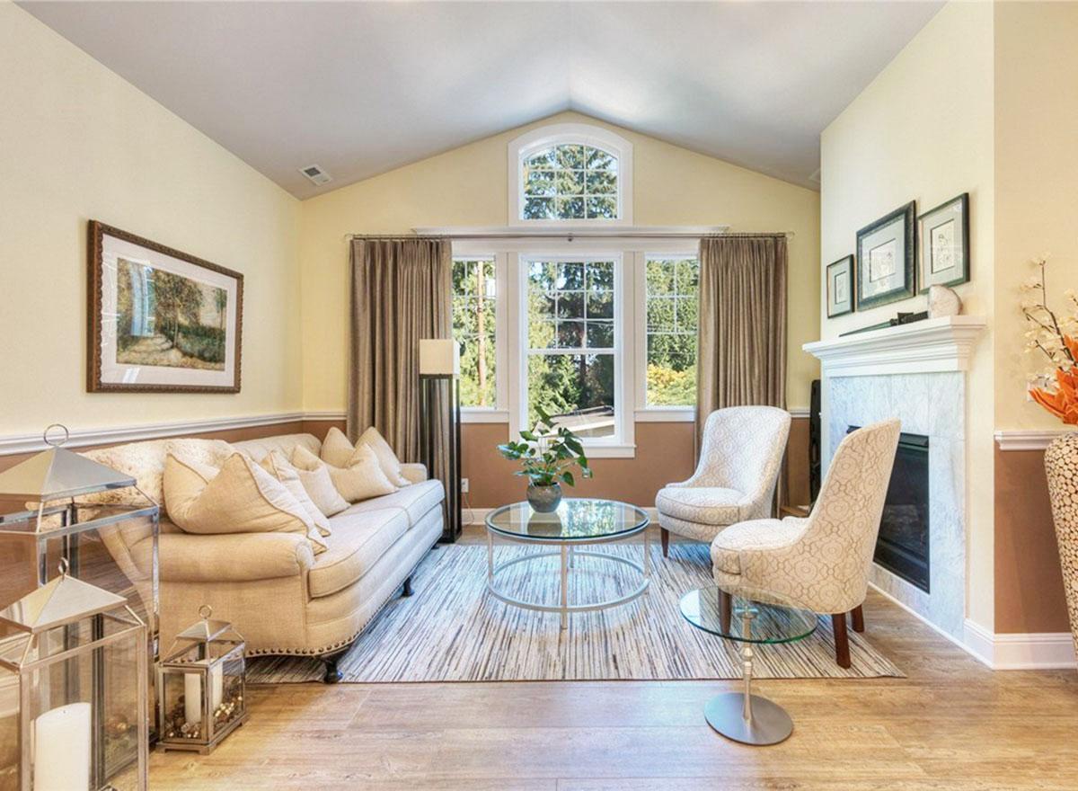 Living room with vaulted ceiling, fireplace, sofa, and arched window.