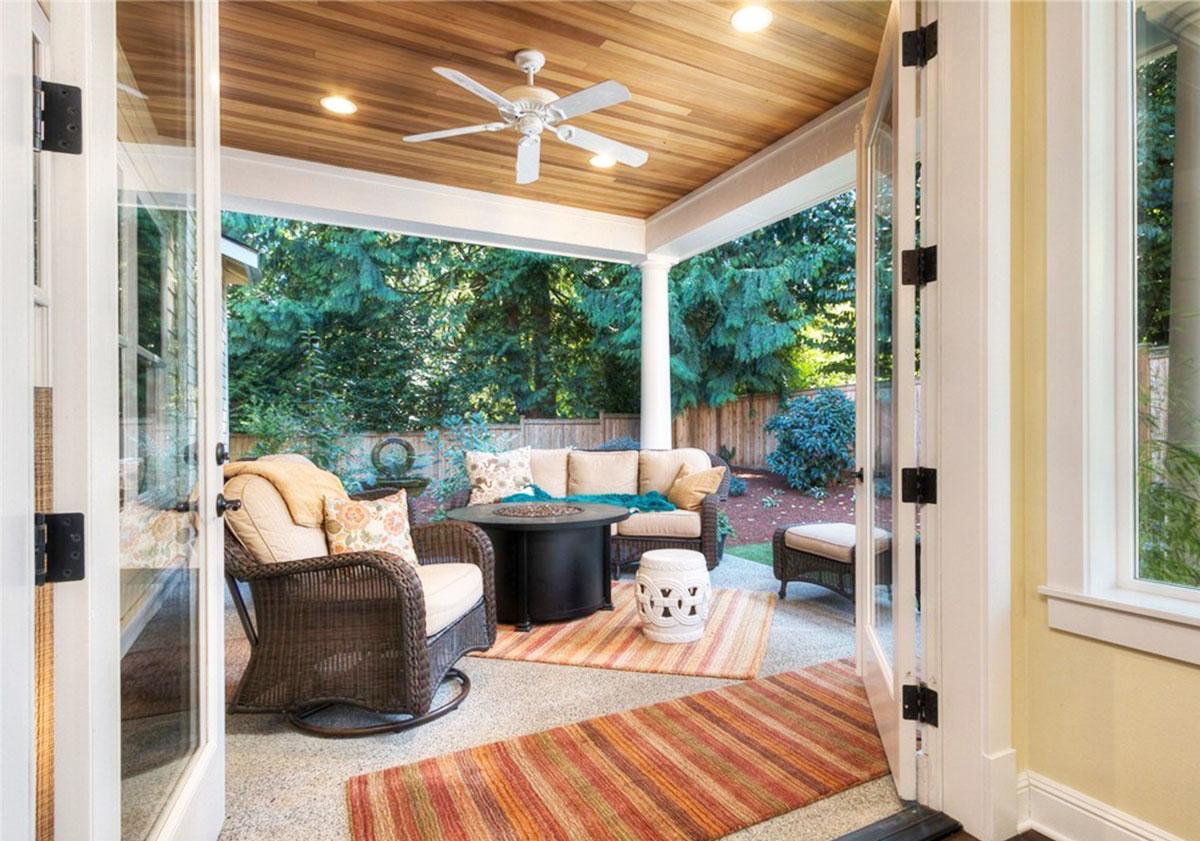 Covered patio with wood ceiling, ceiling fan, and seating area, accessed by french doors.