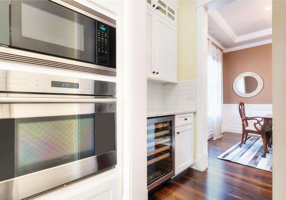 Kitchen area with stainless steel microwave and oven, wine cooler, and view into a dining room.