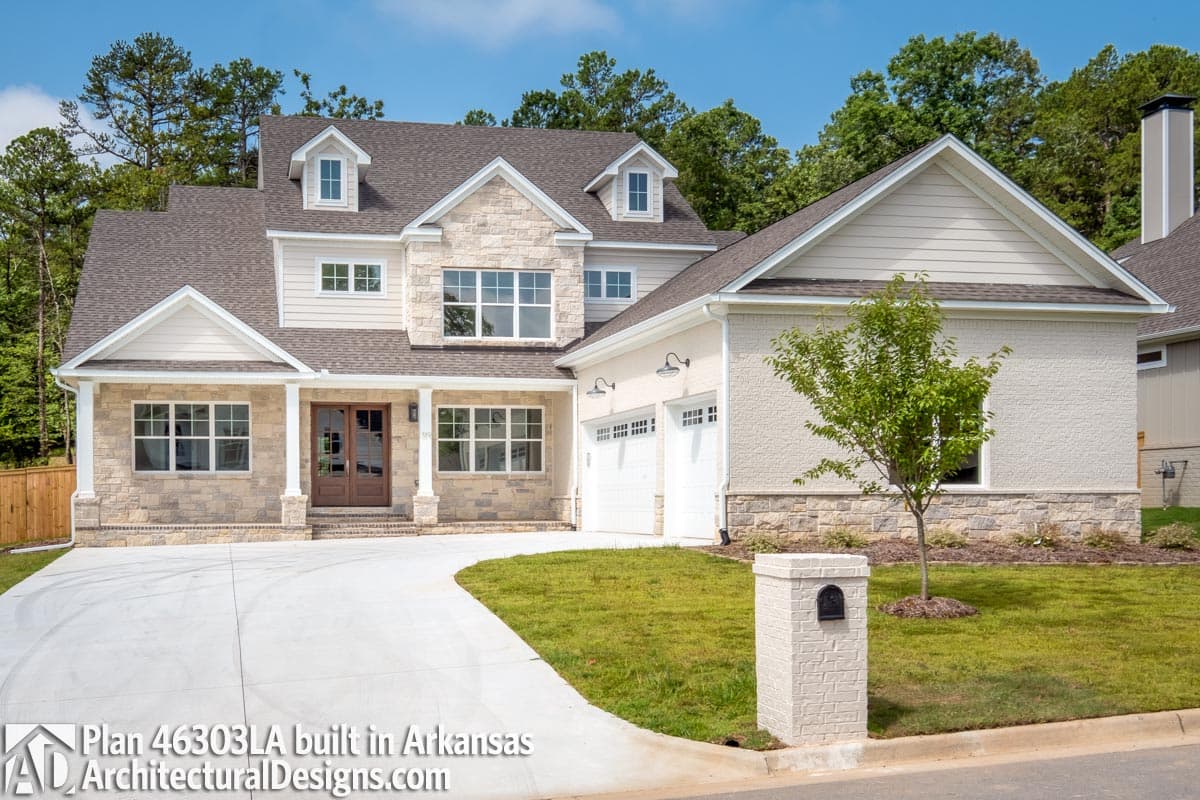 House plan exterior: Two-story modern farmhouse with stone accents, covered porch, dormers, and three-car garage.