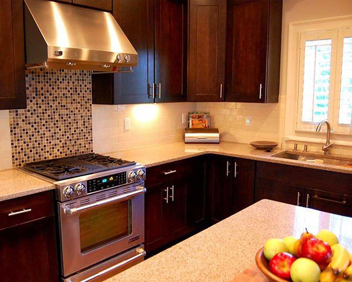Kitchen interior with dark wood cabinetry, granite countertops, stainless steel range with mosaic tile backsplash, and window above sink.