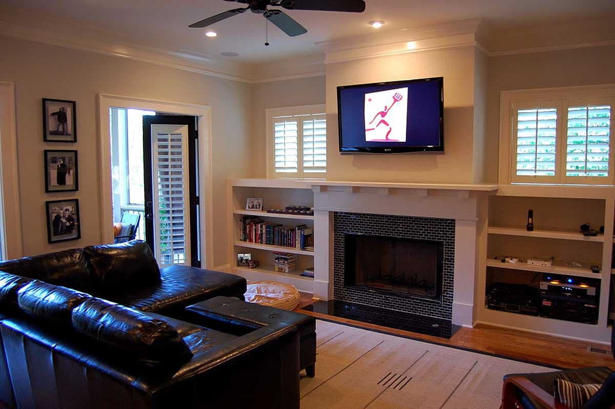 Living room with fireplace, built-in shelves, sectional sofa, and exterior door with shutters.