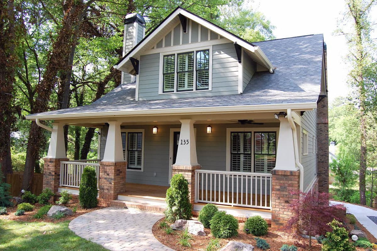 Craftsman house plan exterior: Two-story, prominent gabled dormer, covered front porch with stone pillar accents and white railing.