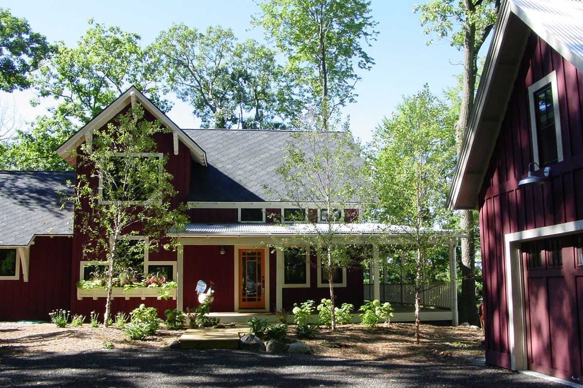 House plan exterior: Two-story, dark red siding, gabled roof, front porch, and attached garage.
