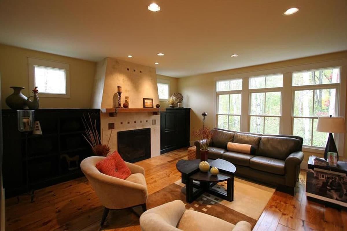 Living room interior with fireplace, leather sofa, coffee table, and a large window wall.