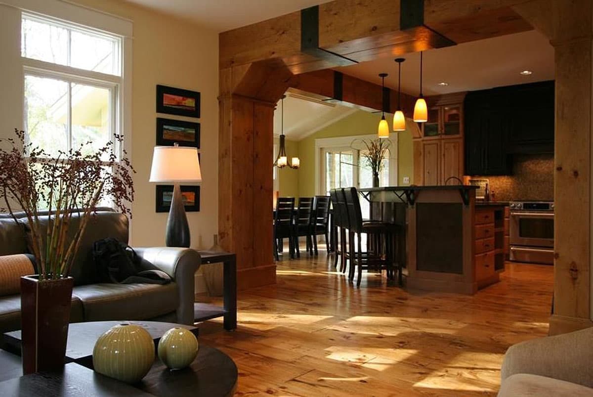 Interior view of open-concept living, dining, and kitchen with wood beams, island, and bar seating.