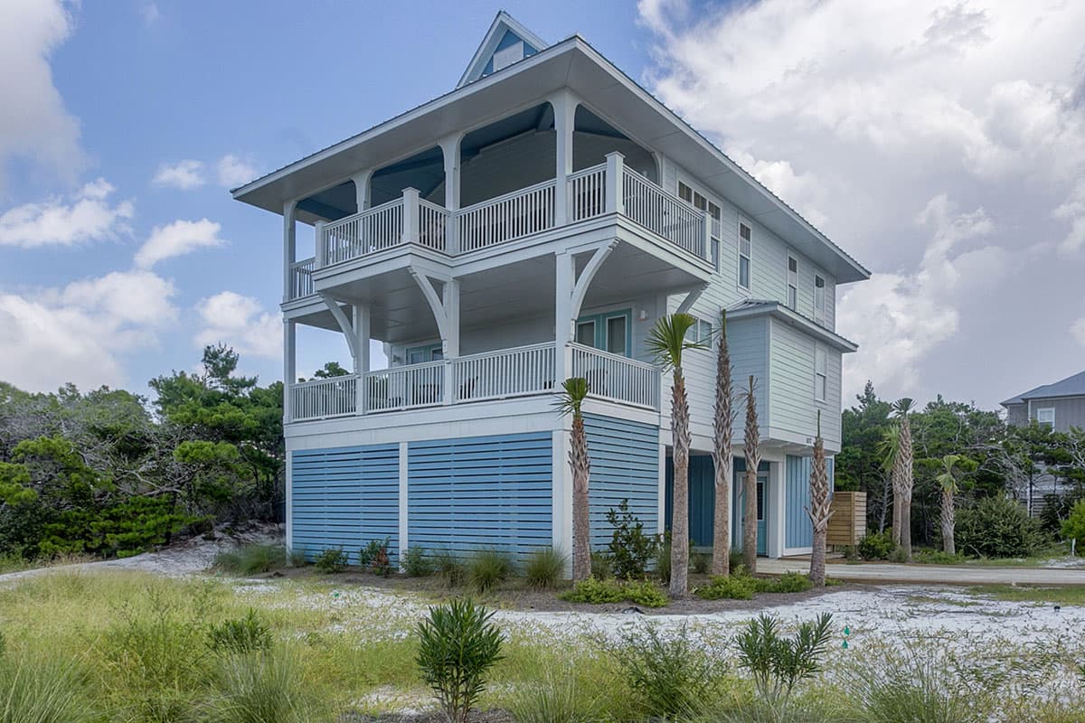 Coastal house plan exterior with two covered balconies, light blue horizontal siding on the lower level, and light blue vertical siding above.