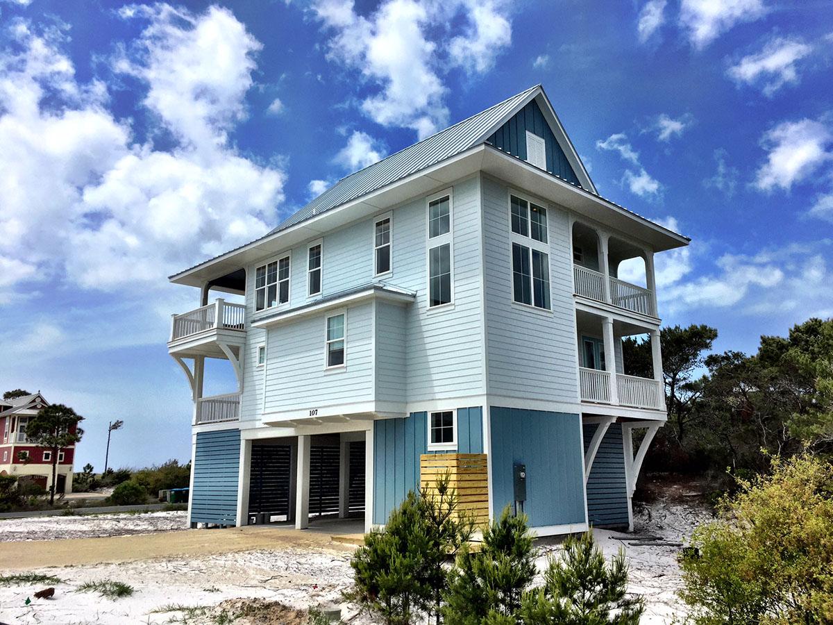 House plan exterior: Two-story coastal home on stilts with multiple balconies, gables, and a metal roof.