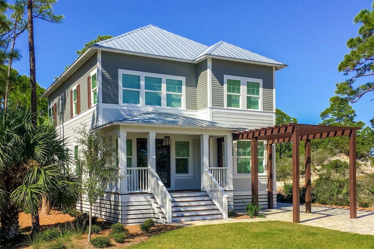 Two-story house plan exterior with a metal roof, front porch with columns, and a wooden pergola.