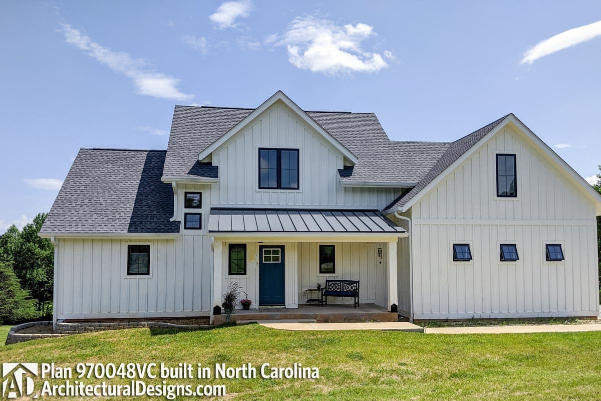 Modern Farmhouse house plan exterior with white board and batten siding, dark windows, gables, and a metal porch roof.