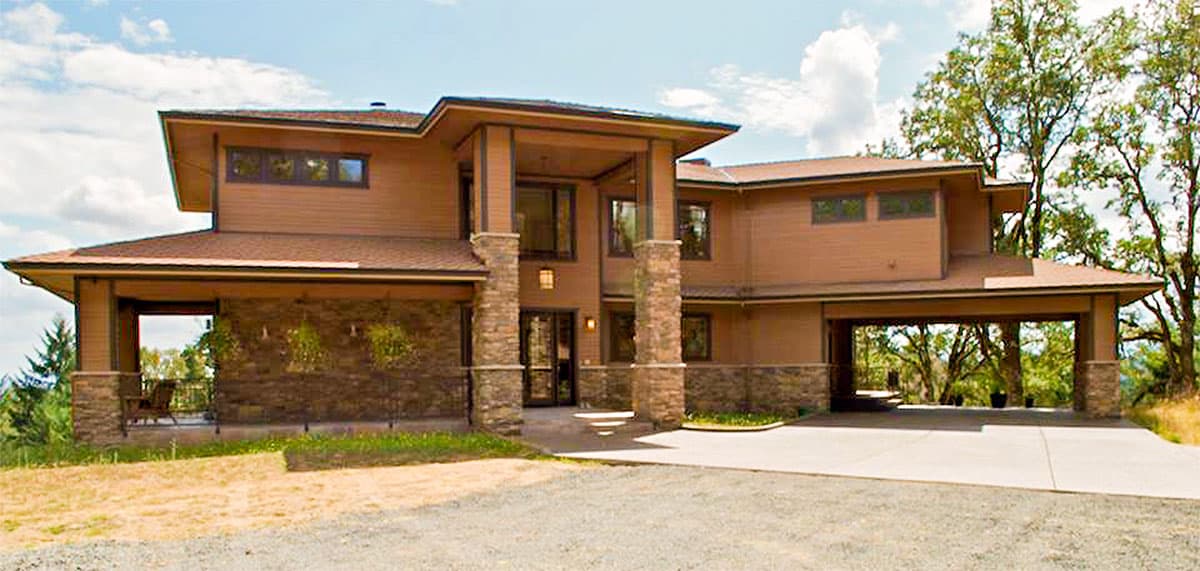 House plan exterior. Two-story home in a modern style with a porte-cochere, covered porch, and a flat roof with extended eaves.
