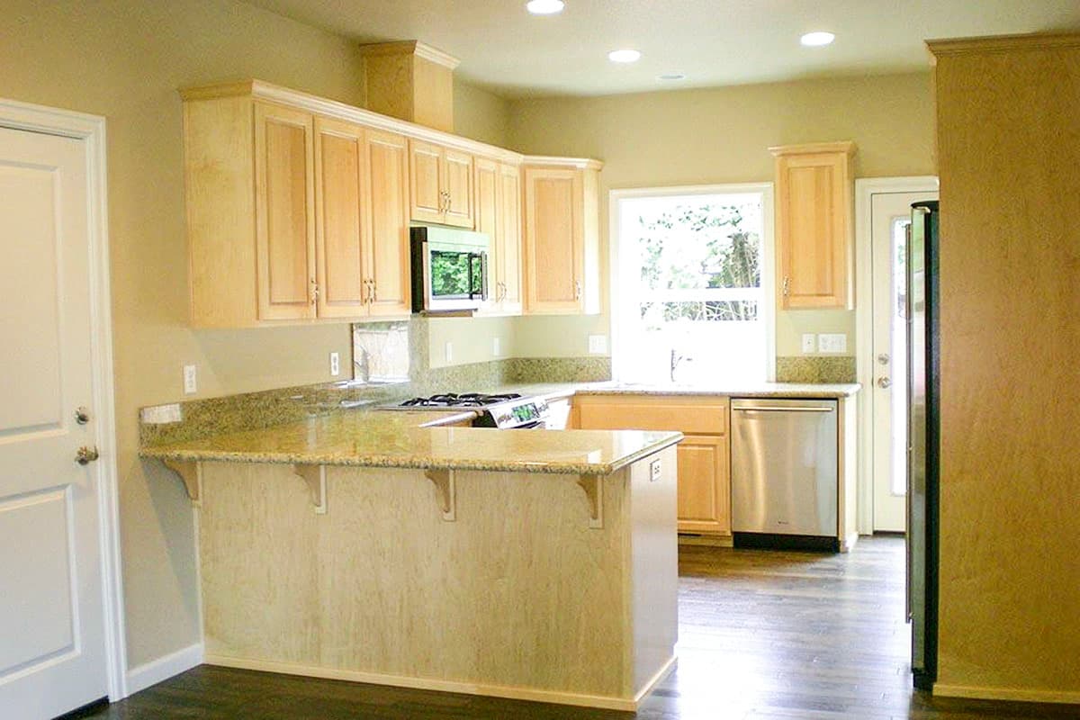 Kitchen interior with light wood cabinets, granite countertops, stainless steel appliances, and a peninsula.