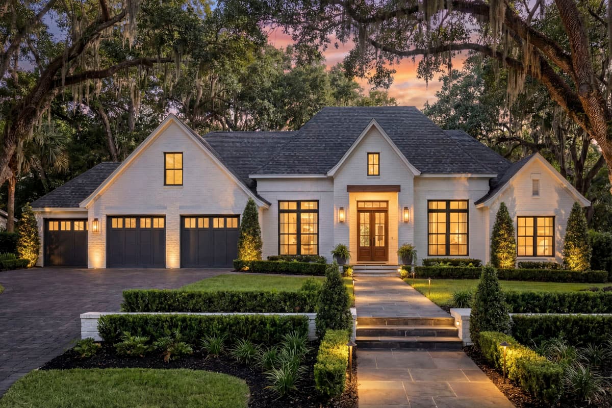 House plan exterior: Modern Farmhouse style, one story, white brick, multiple gables, three-car garage, large windows, covered entry.
