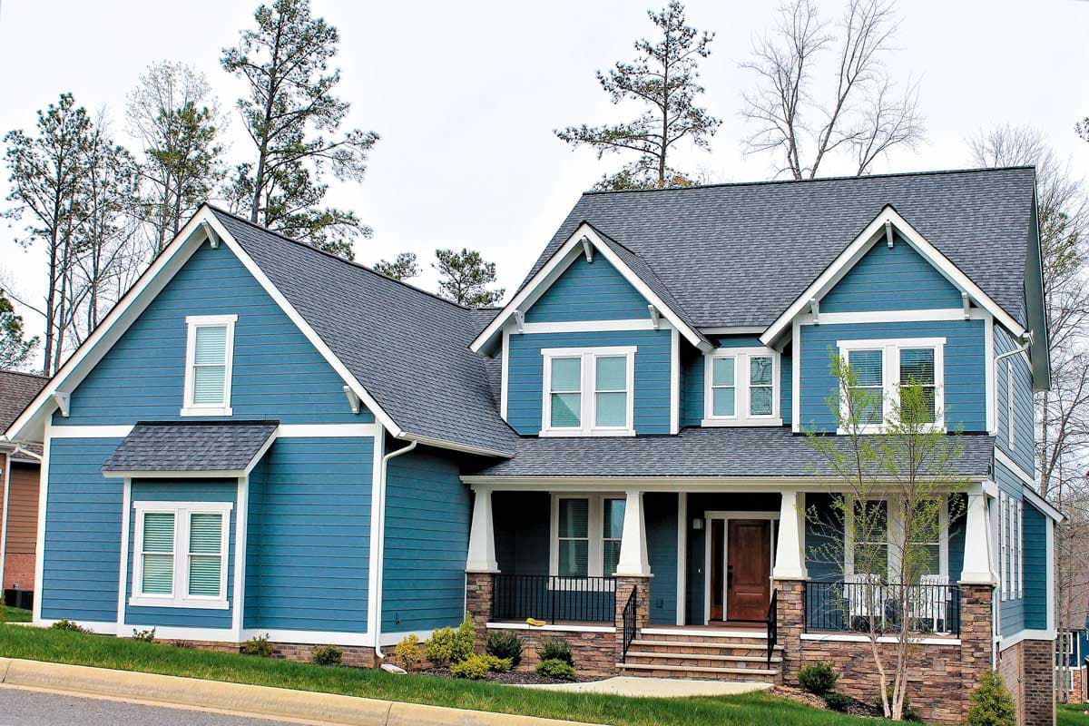 Two-story Modern Farmhouse exterior with blue siding, white trim, gabled rooflines, and a covered front porch with stone supports.