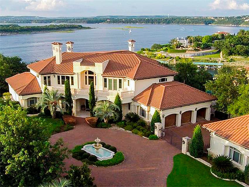 House plan exterior. Two-story Mediterranean-style home with tile roof, arched windows, covered entry, and attached three-car garage.