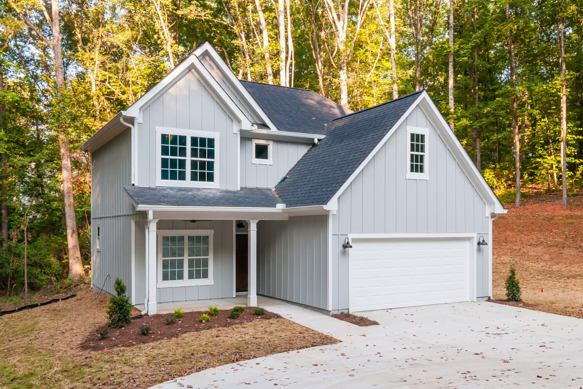 House plan exterior: Two-story house in a farmhouse style with gabled rooflines, a front porch, and an attached garage.