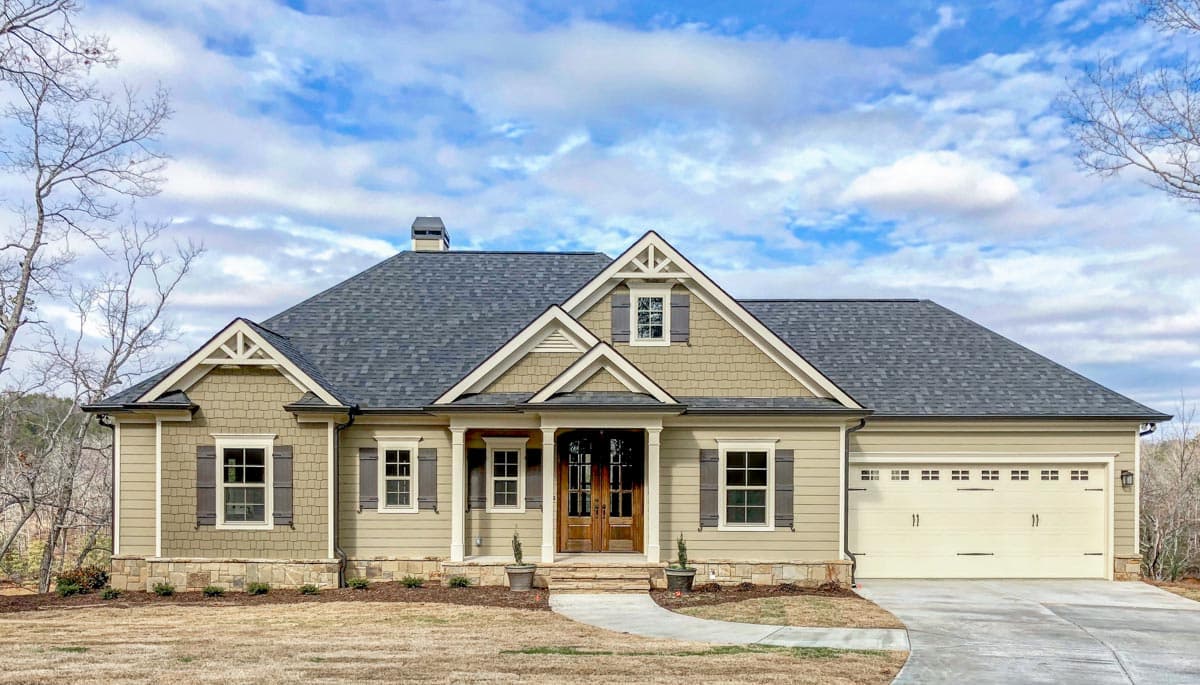 House plan exterior. Craftsman style, one-story home with a gabled roof, front porch, and attached garage. Includes dormers and shutters.