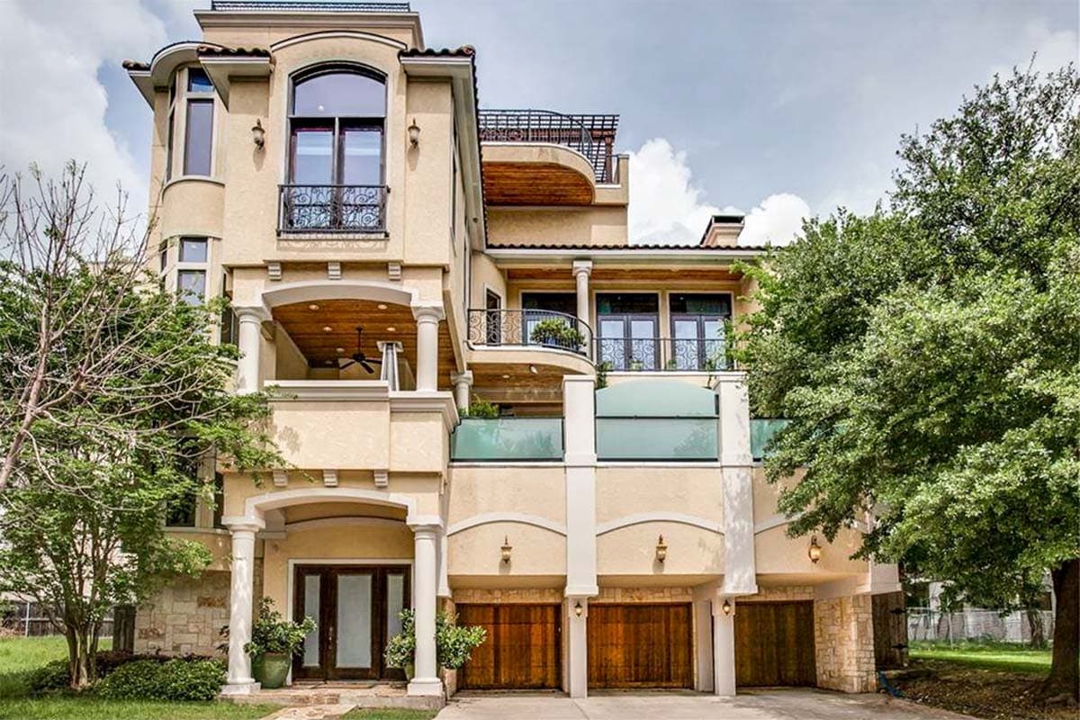 House plan exterior. Mediterranean style, three stories, featuring arched entryways, balconies with wrought iron railings, and multiple garage bays.