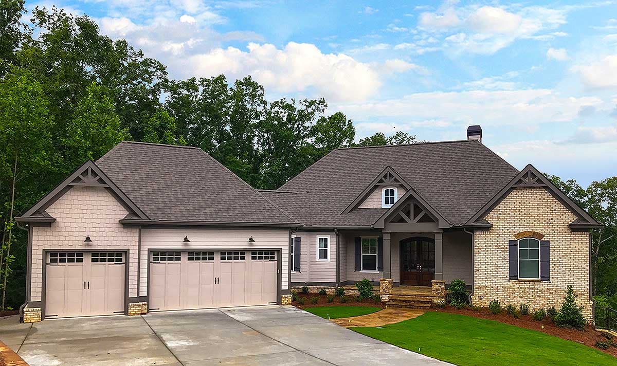 House plan exterior: Ranch style with three-car garage, prominent gables, stone accents, and covered entry porch.