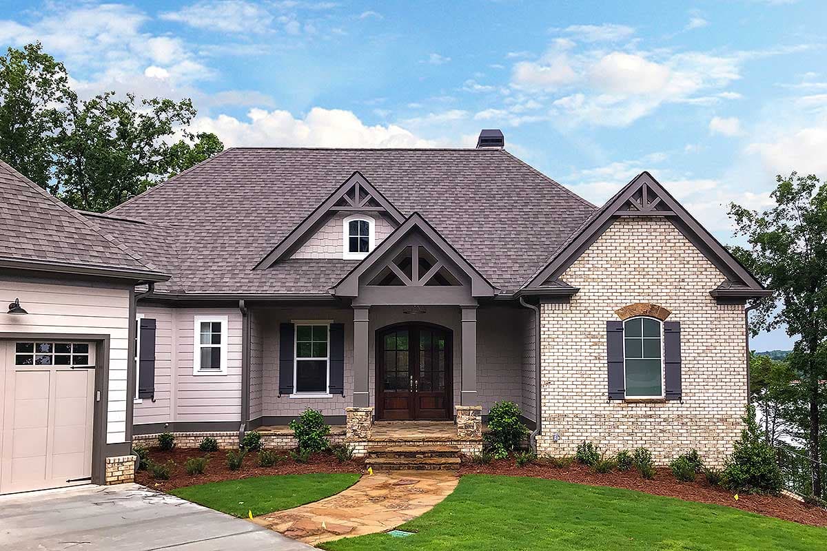 House plan exterior: Craftsman style, two stories, prominent gabled entrance with stone accents, side-entry garage.