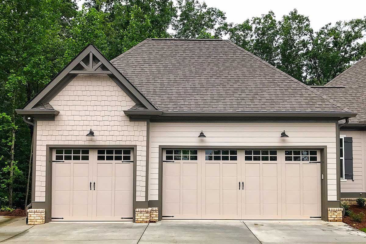House plan exterior: Modern Farmhouse style, 3-car garage with upper windows, shake siding and gabled dormers.