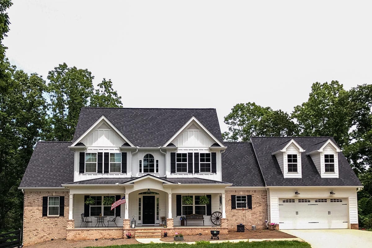 House plan exterior: Two-story Modern Farmhouse with brick and white siding, prominent gables, and a side-entry garage.
