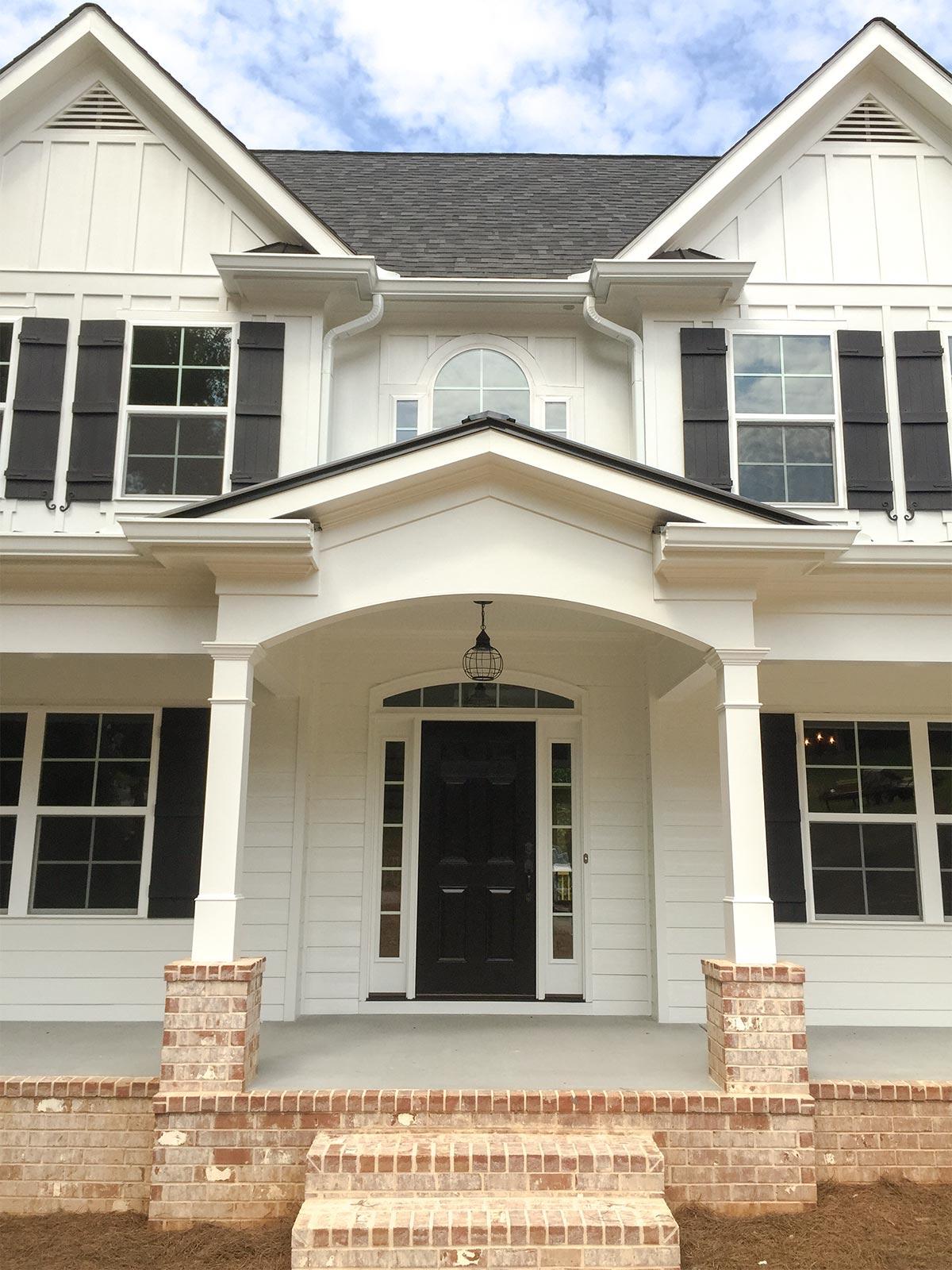 Modern Farmhouse exterior with covered porch, arched entryway, double gables, board-and-batten siding, and brick accents.