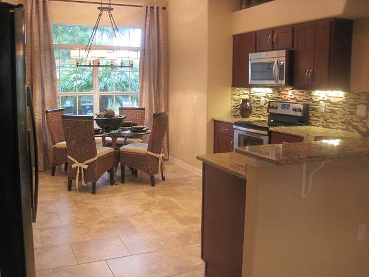 Interior view of an open-concept dining area and kitchen with a dining table, four chairs, and a kitchen island with granite countertops.
