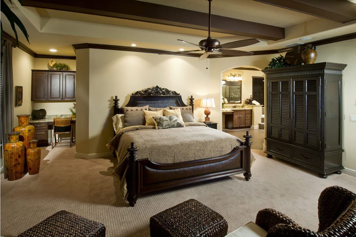 Bedroom with dark wood furniture, ceiling fan, recessed lighting, and an arched doorway to an ensuite bathroom.