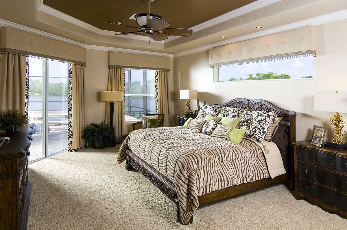 Bedroom rendering with tray ceiling, king bed, sliding glass door to patio, and large windows.