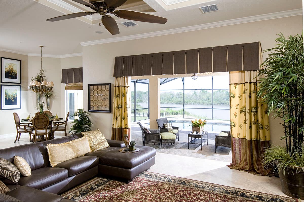 Open-concept living area with sectional sofa, dining set, and view to screened pool and water.