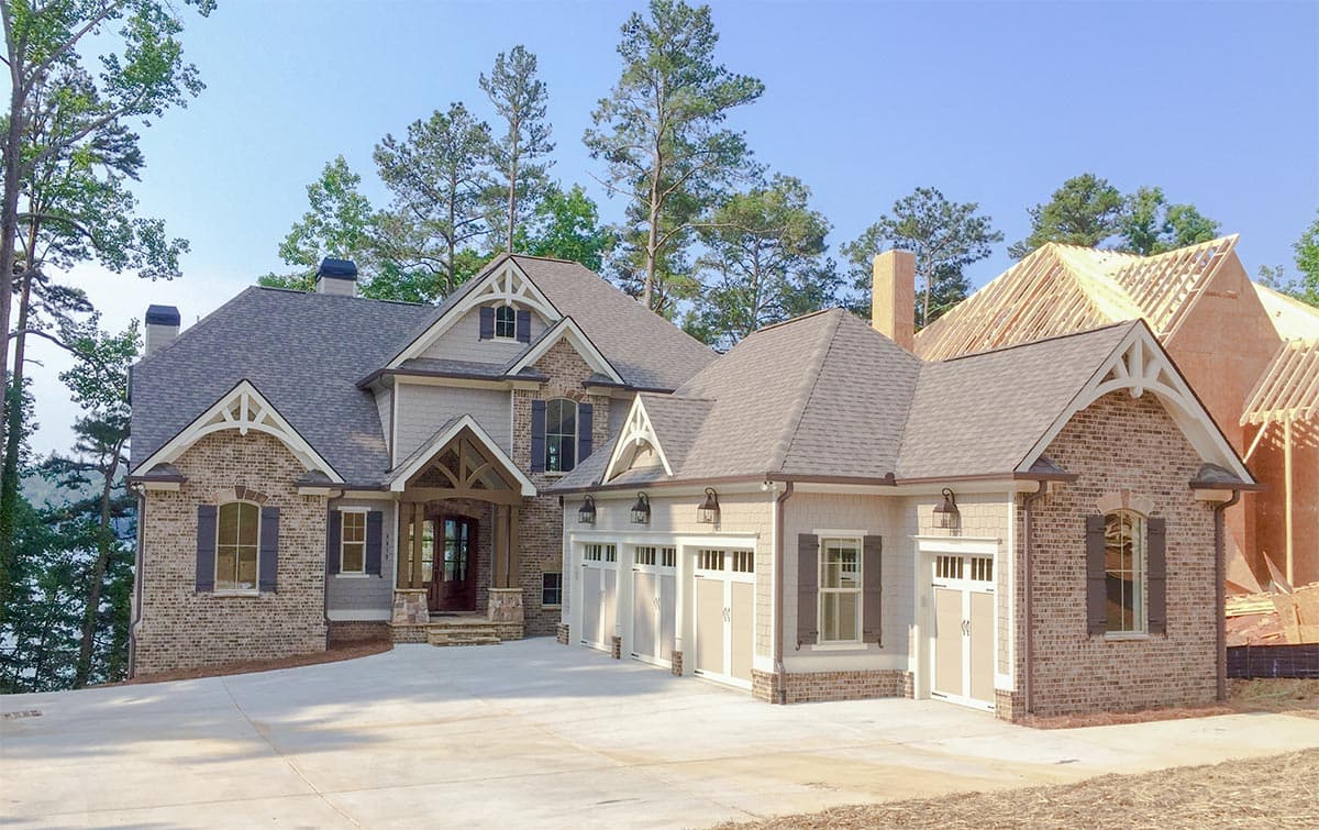 Two-story house plan exterior with brick and siding, multiple gables, a covered entry, and a four-car garage.