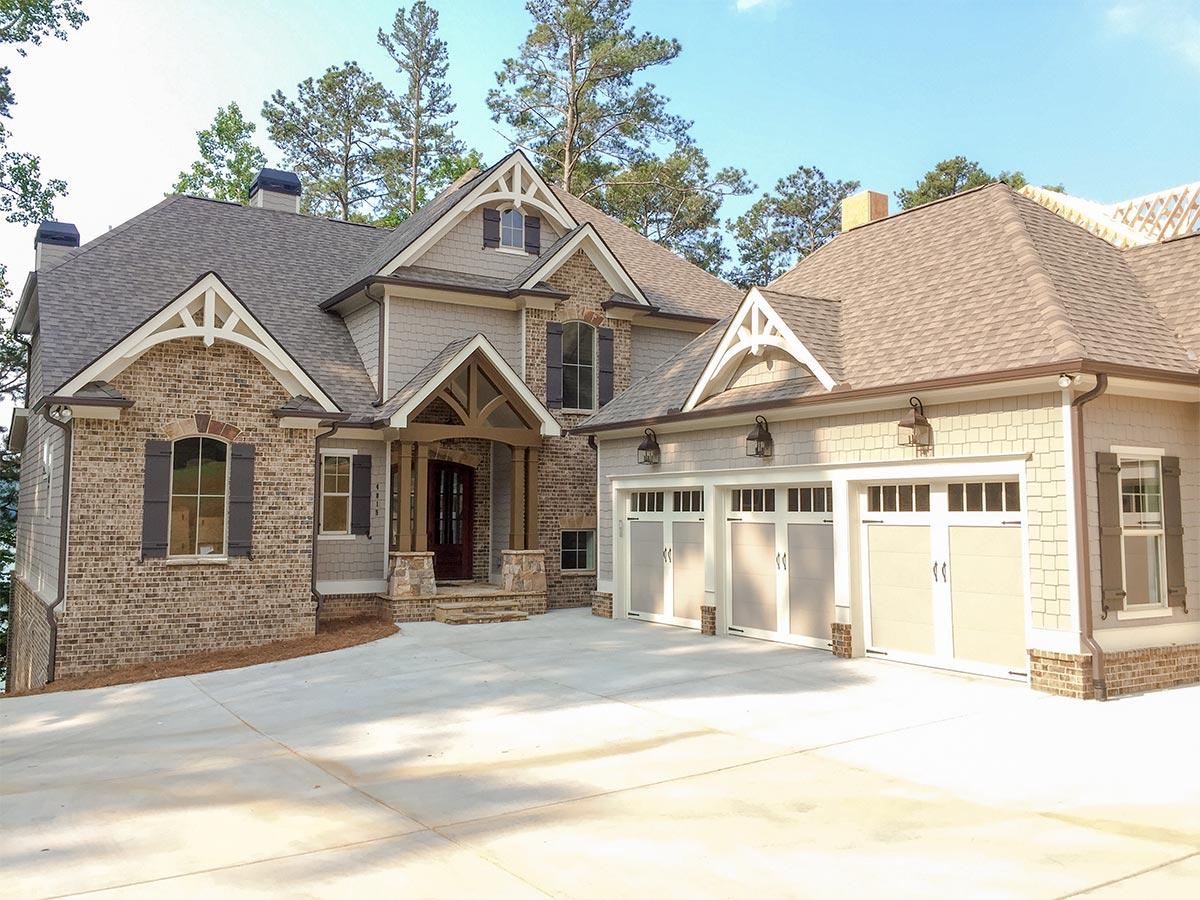 House plan exterior. Two-story home with Craftsman details, brick and shingle siding, covered front porch, and three-car garage.