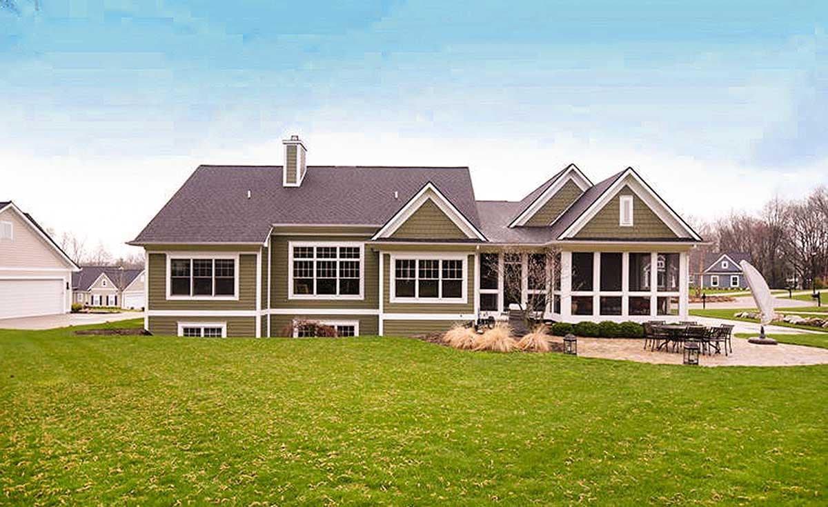 House plan exterior: green siding, multi-level roof, multiple gables, screened porch, and large windows.