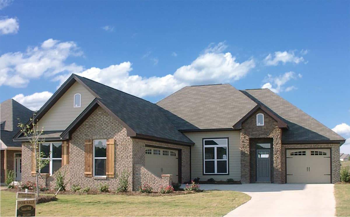 House plan exterior. One-story house with brick and siding facade. Features include gabled roof, dormers, and attached garage.