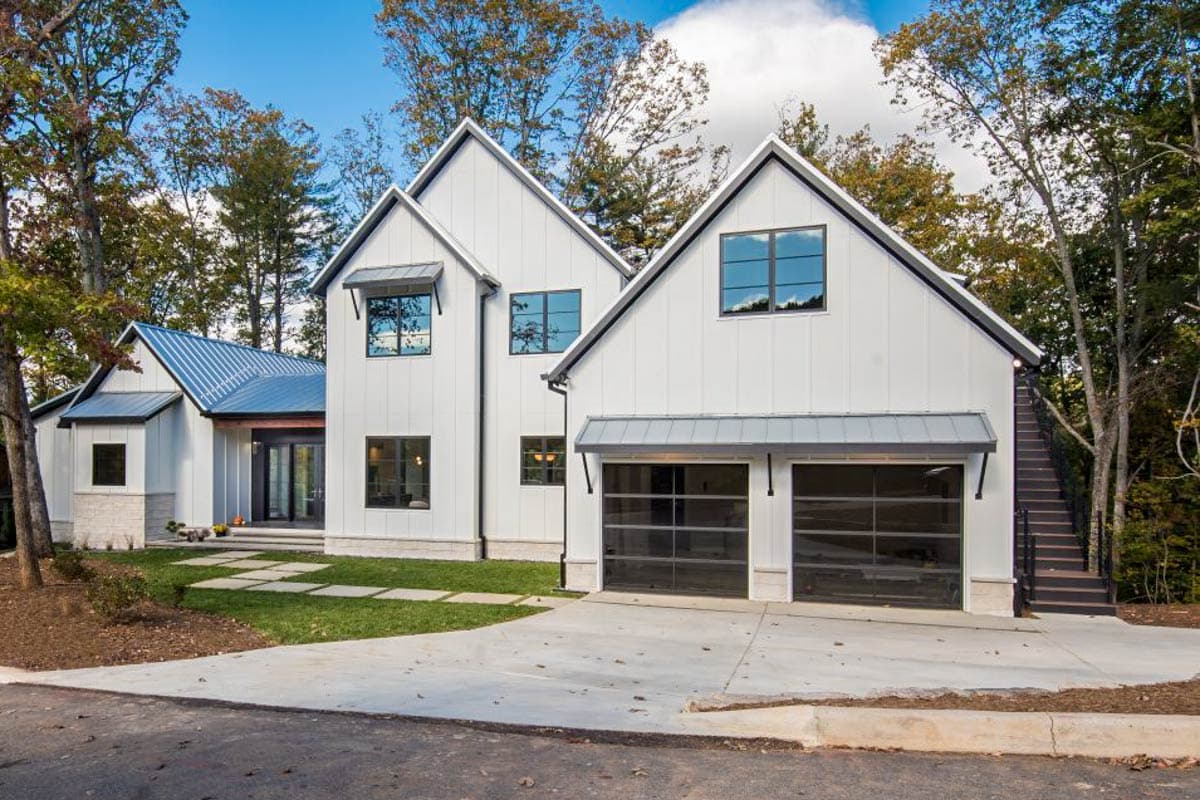 House plan exterior. Modern Farmhouse style, two-story home with multiple gabled rooflines, awning over garage, and a detached stairwell to the side.